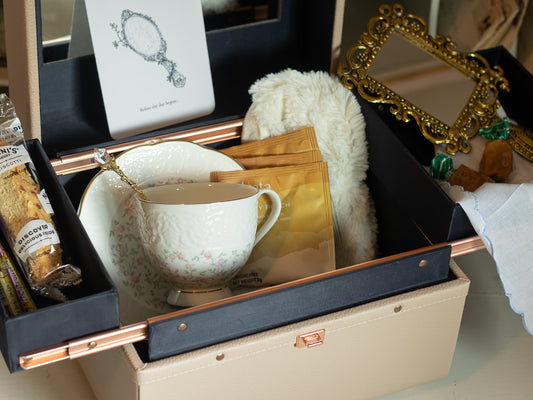 Close-up of the Reflections at the Threshold bridal gift featuring a floral teacup and saucer, tea packets, reflection card, ornate hand mirror, and keepsake case details.