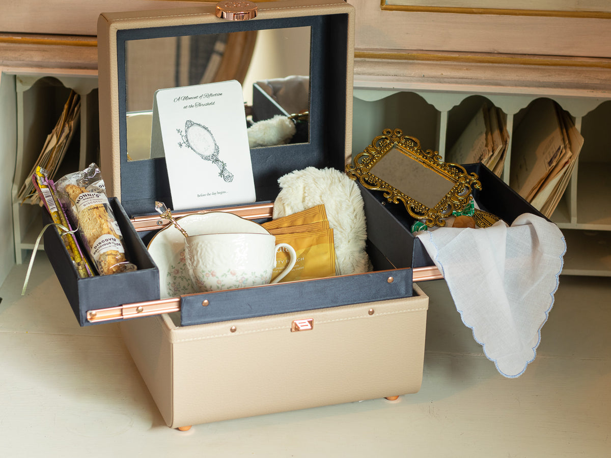 Reflections at the Threshold bridal gift arranged in a keepsake vanity/train case with teacup, tea, biscotti, reflection card, vintage-style mirror, handkerchief, and comfort items.