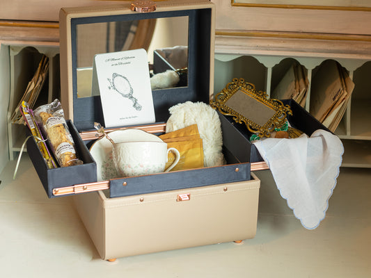 Reflections at the Threshold bridal gift arranged in a keepsake vanity/train case with teacup, tea, biscotti, reflection card, vintage-style mirror, handkerchief, and comfort items.