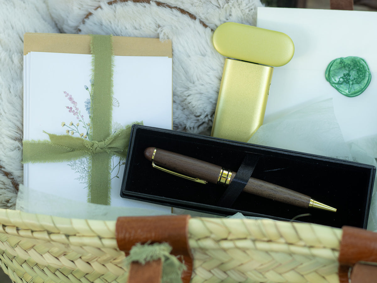 Close-up of a woven gift tote with body butter, lotion, stationery, a pen, and soft comfort items arranged inside.
