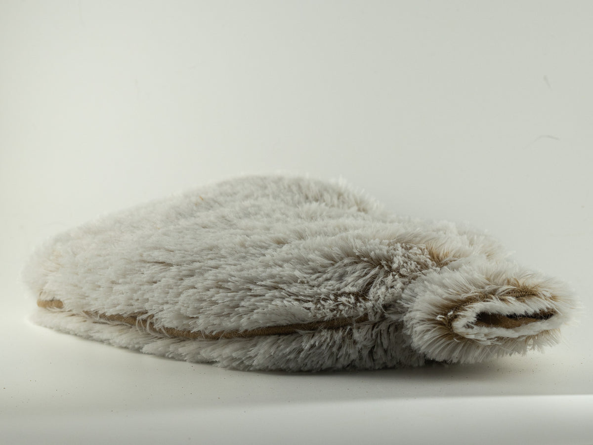 Ivory plush Warmies hot water bottle-shaped heat pack photographed on a soft white background.