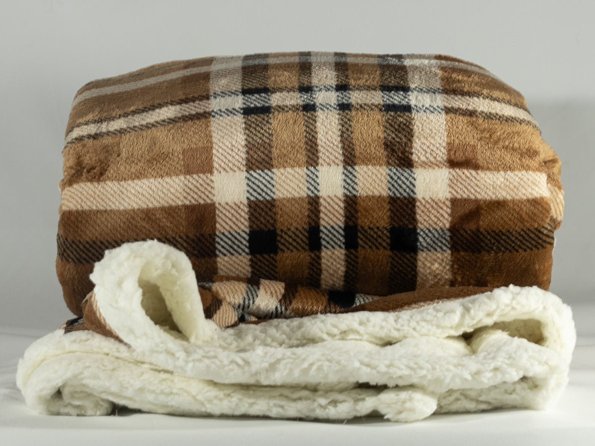 Brown, cream and black plaid sherpa blanket folded to show its soft cream fleece lining.