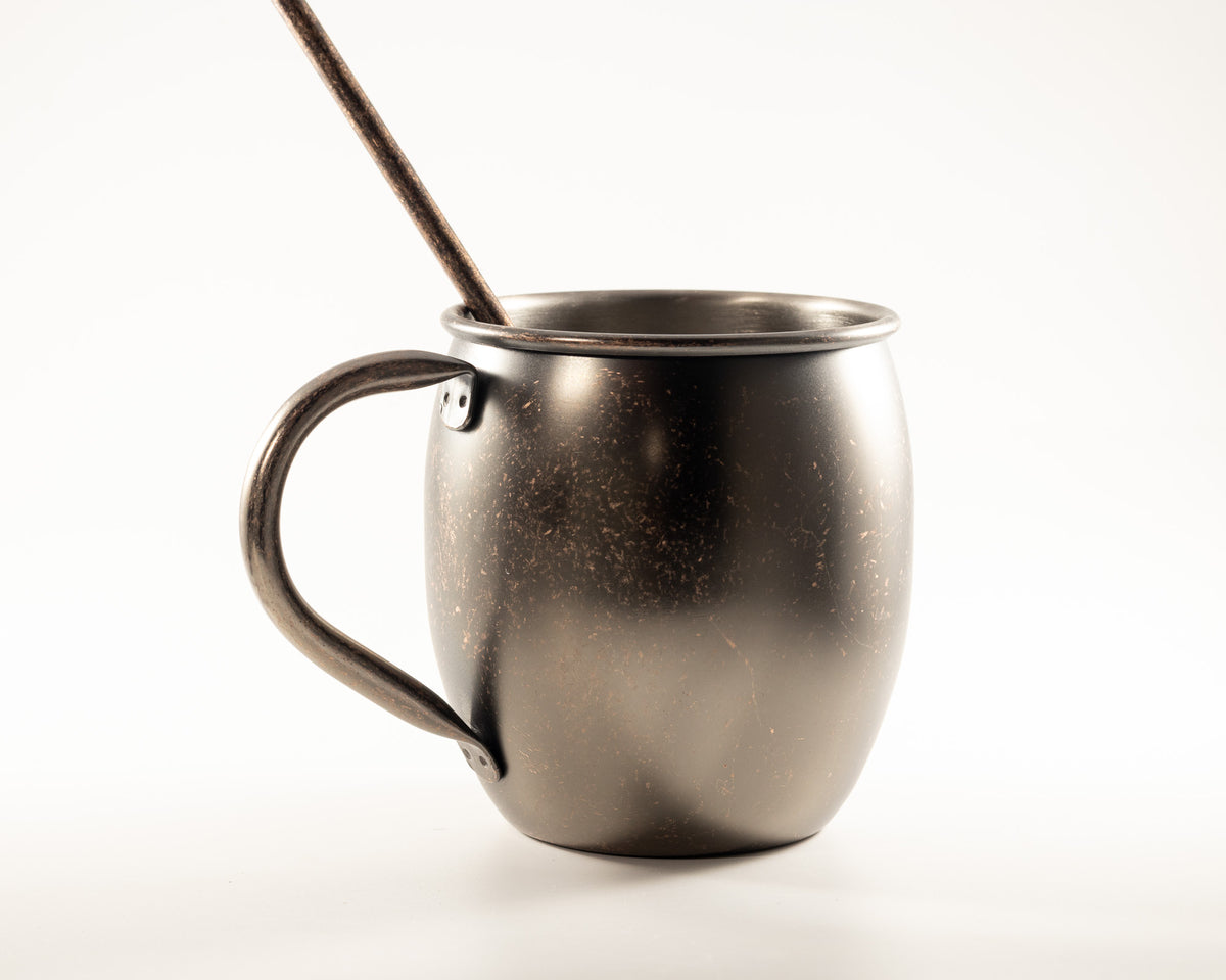 Antiqued copper mule mug with a rustic aged finish and matching stir stick, perfect for cozy beverages and thoughtfully curated gift baskets.