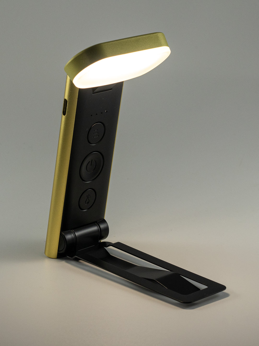 Compact folding rechargeable book light with black and gold finish, shown illuminated for The Irish Daisy gift collection.