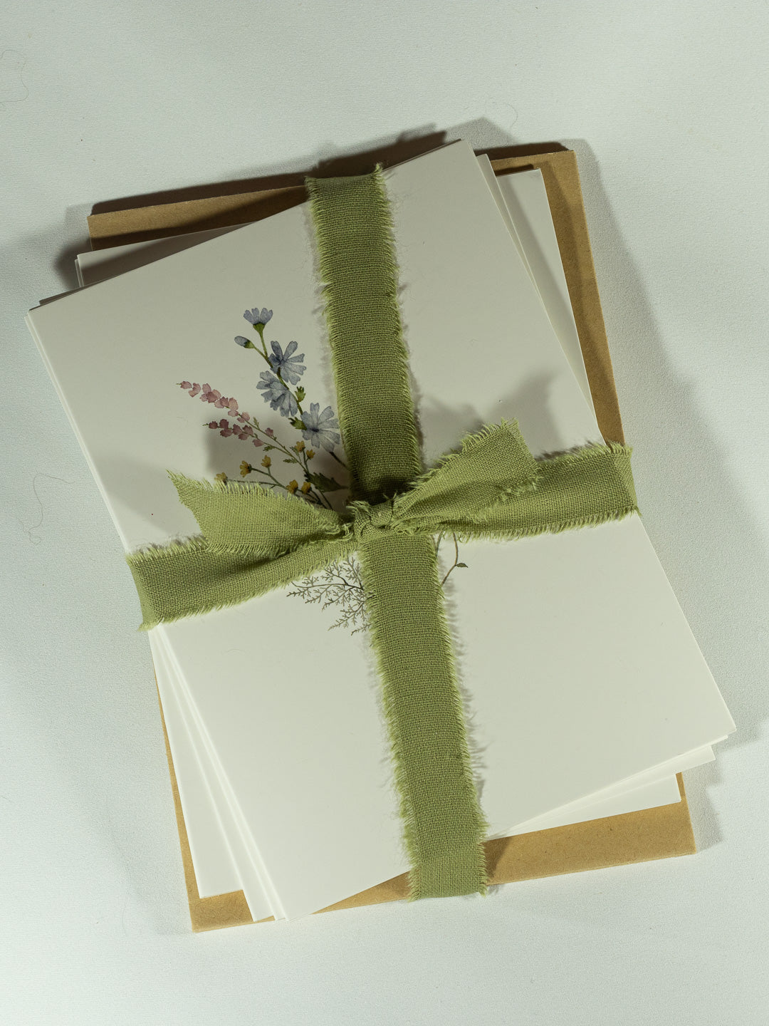 Cream stationery and note cards tied with soft sage ribbon and finished with a delicate botanical print.