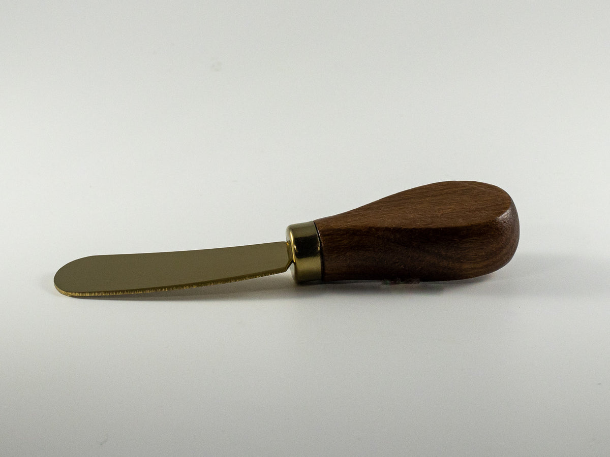 Small spreader with warm wood handle and brass-tone blade for The Irish Daisy gift collection.