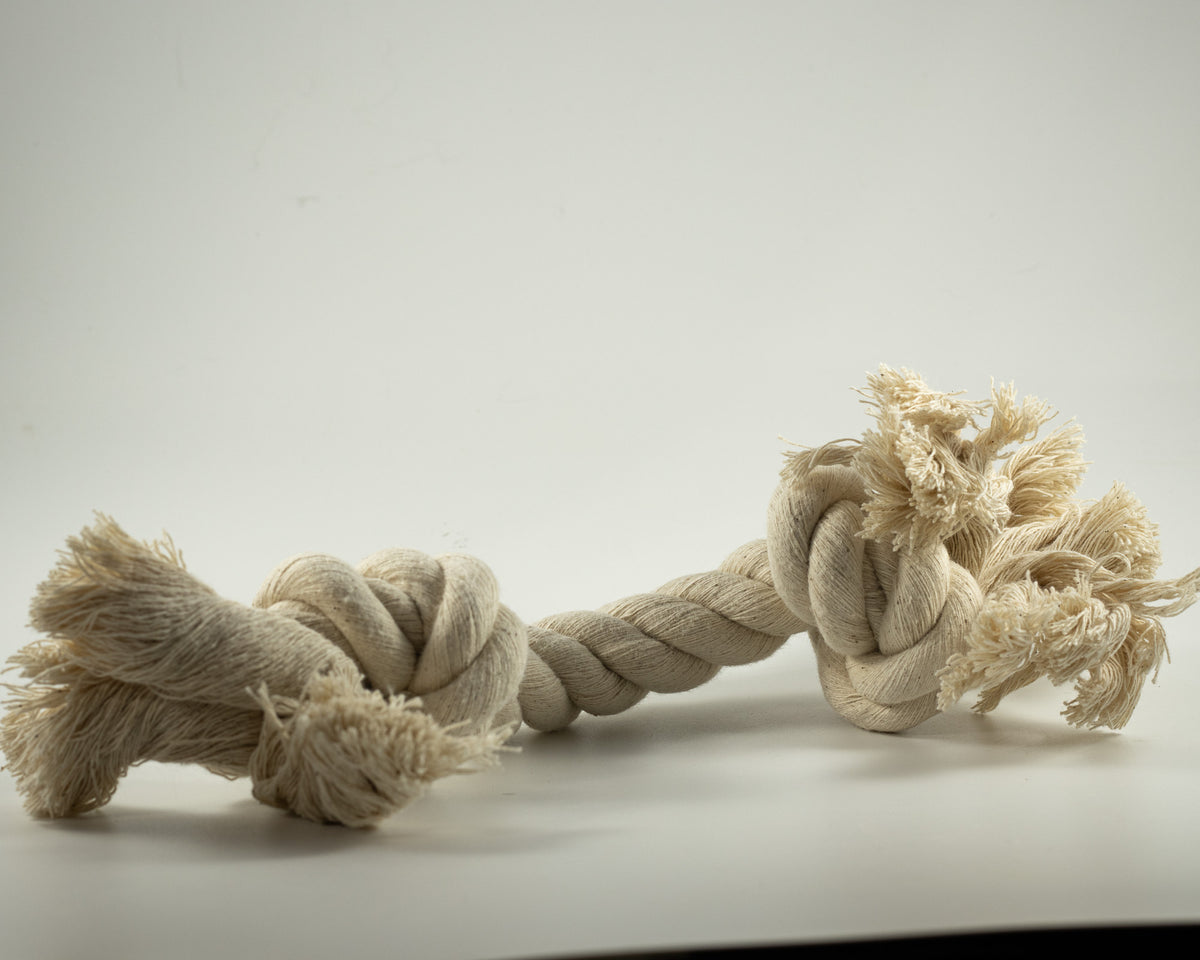 A natural beige cotton rope dog toy with knotted ends.