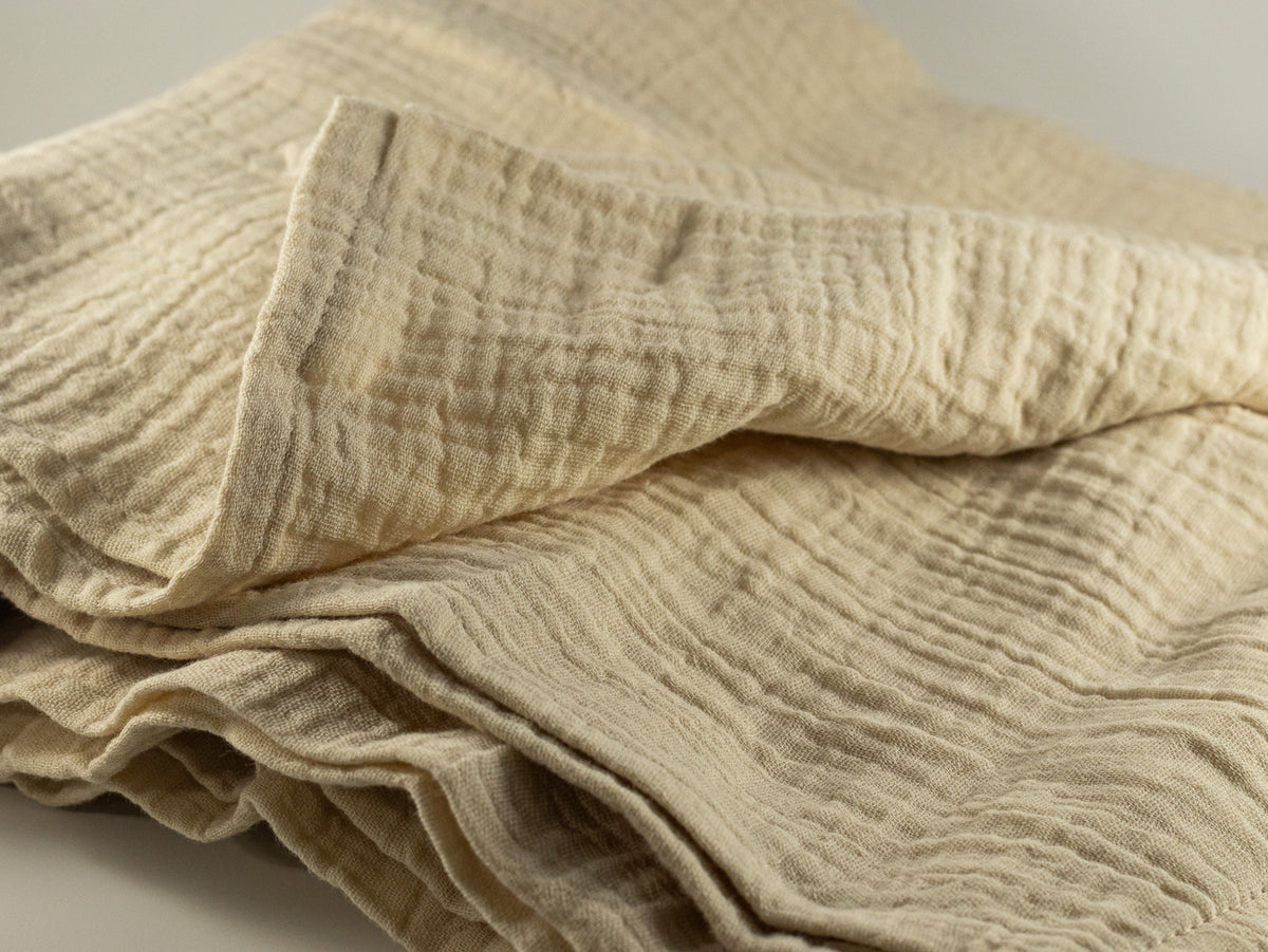 Soft cream muslin baby blanket with crinkled texture and stitched edge