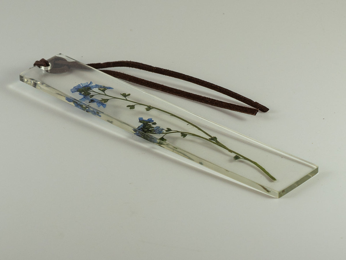 Clear glass bookmark with pressed blue flowers and brown leather cord