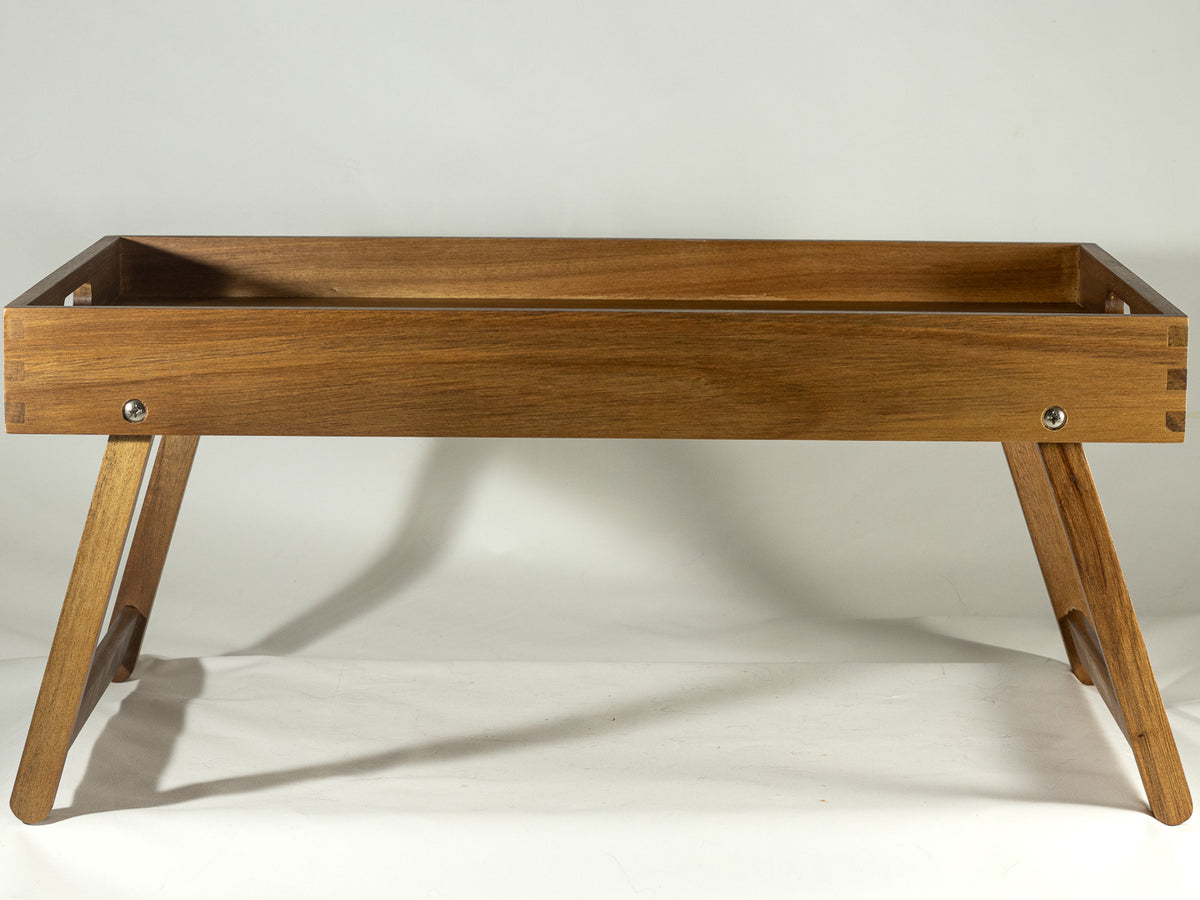 Wooden serving tray with angled folding legs photographed on a soft white background.
