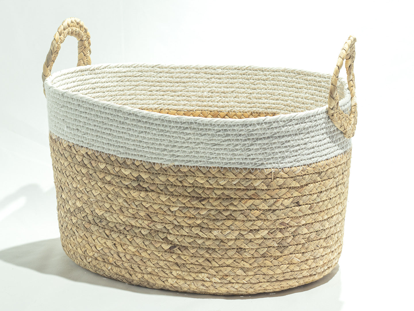 A woven storage basket with a natural seagrass body, a white rope trim, and two rope handles.